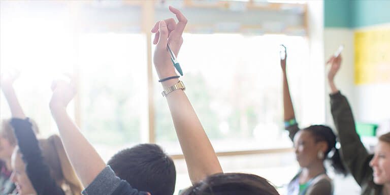 Students raising their hands to answer a question in a classroom