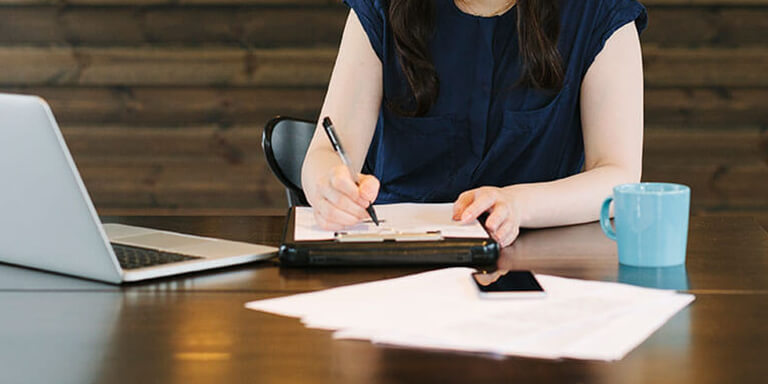 A woman taking notes on a clipboard at an office table