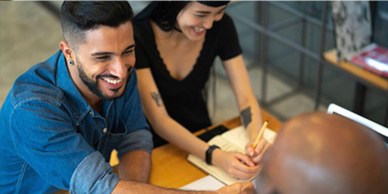 A man and a woman in a meeting shaking hands with another man and smiling 