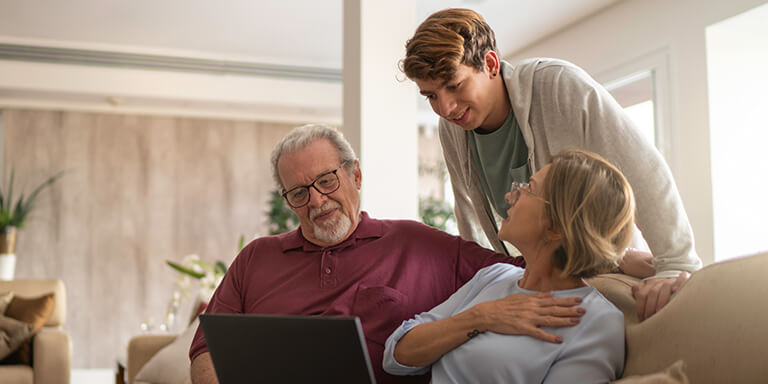 Grandparents looking at photos with their grandson on a sofa