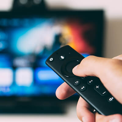 Close-up of a TV remote against a flat-screen TV 