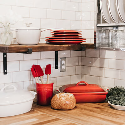 A corner of a kitchen showcasing various plates and bowls and a loaf of bread