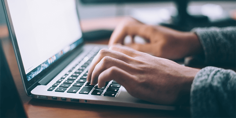 Close up of a woman typing on the keyboard of her laptop computer