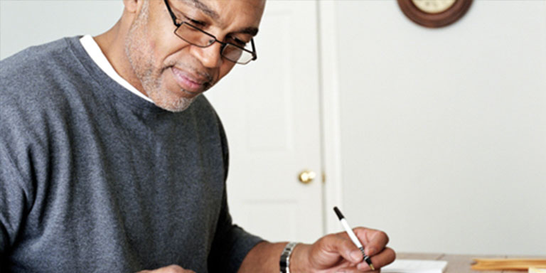 A middle-aged man doing his expenses with his receipts and a calculator on his desk 