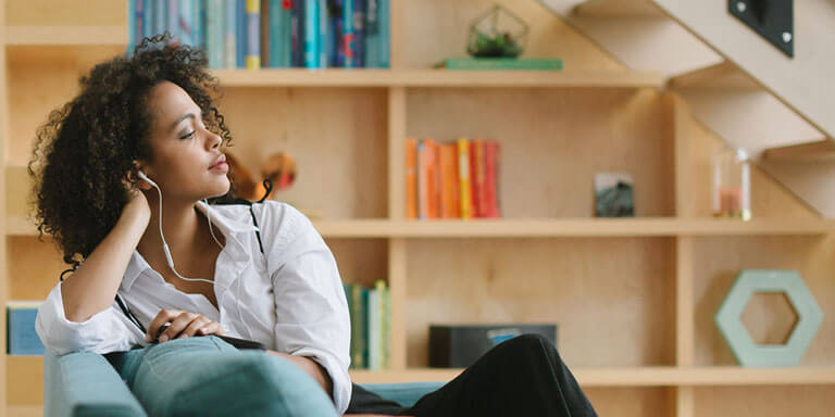 Young woman listening to music with headphones on the couch in her living room