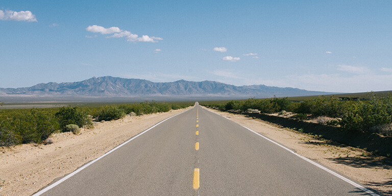 Wide open highway road with mountain ranges in the background