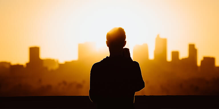 A person watching the sun set over a city skyline