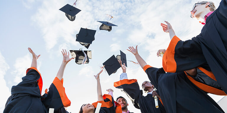 A group of college students at graduation throwing their caps into the air