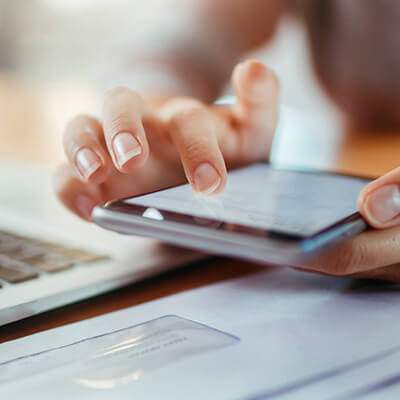 Close up of a woman paying her bills using her smartphone