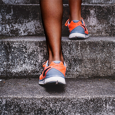 A woman in running shoes walking up concrete steps