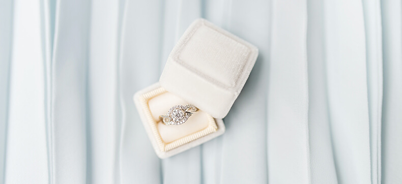 A diamond engagement ring in an open white leather box 