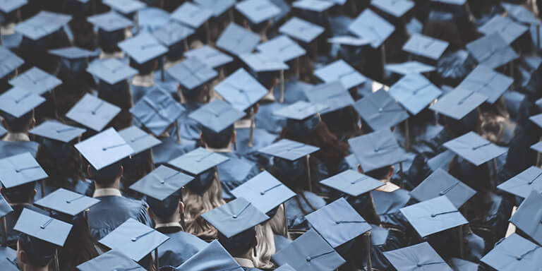 Overhead view of students at a graduation ceremony in blue caps and gowns