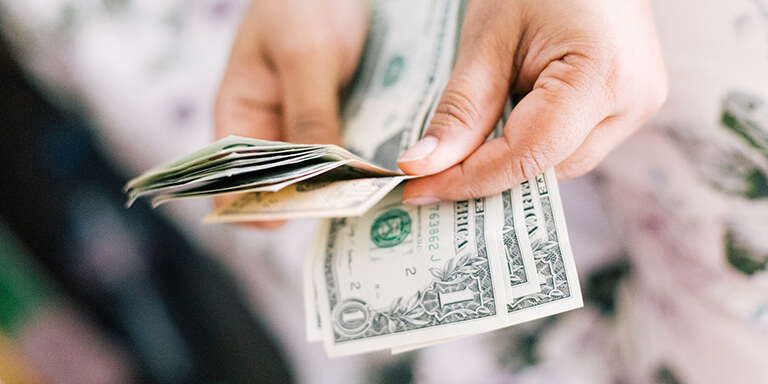 Close up of a woman holding a stack of dollar bills