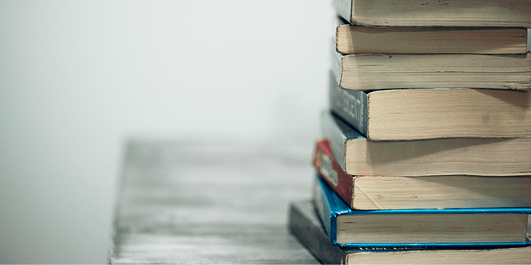 A stack of weathered books resting on a wooden table