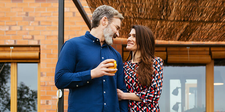 A couple gazing at each other on the porch outside of their home