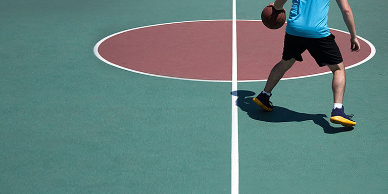 A man wearing athletic clothes playing basketball on a basketball court