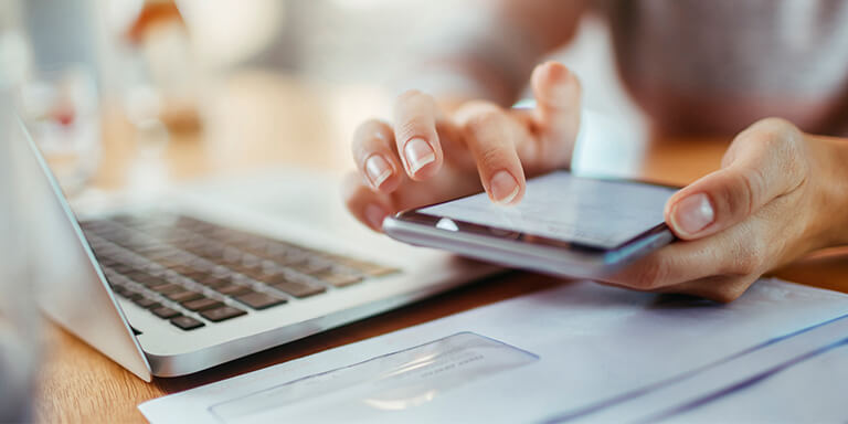 Closeup of a woman using her smartphone to pay her bills