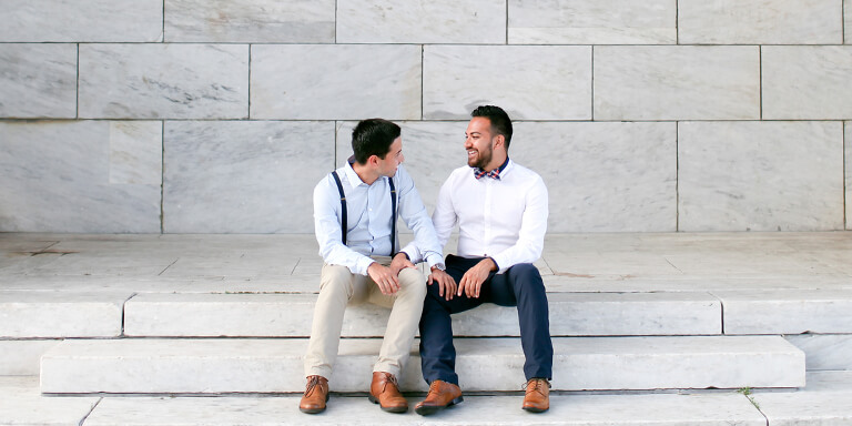 A couple sitting on marble steps facing one another and smiling