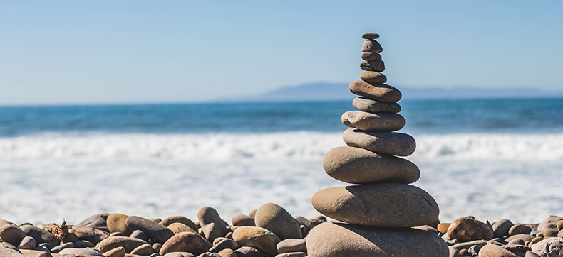 A cairn of beach rocks in front of the ocean 