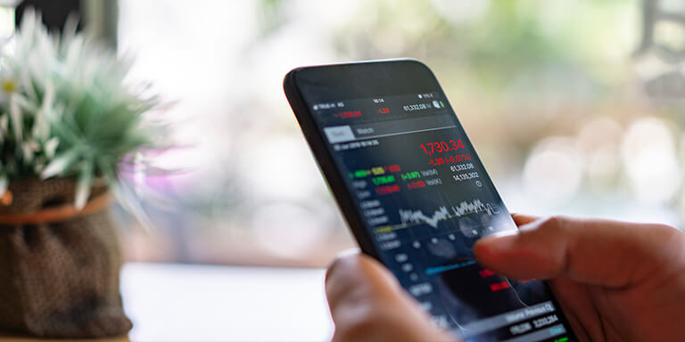 Close up of a person holding a smart phone with stock information on the screen