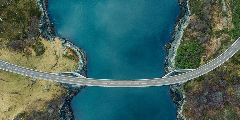 Overhead view of a bridge connecting two pieces of landing over a river 