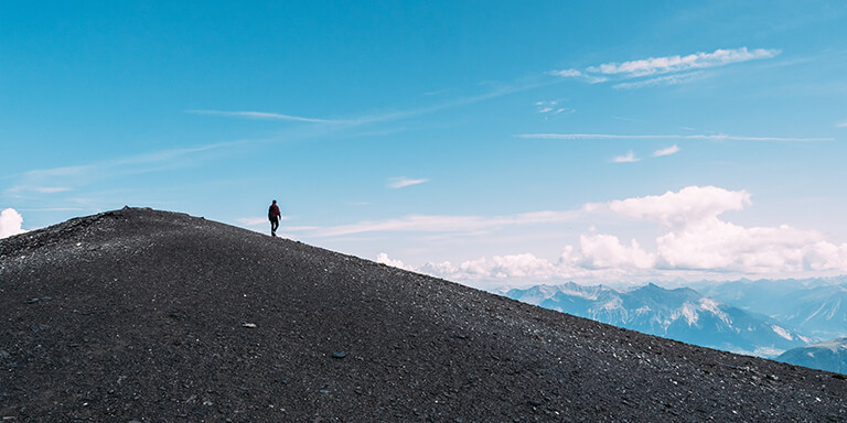 Solo person standing on the top of a mountain overlooking the rest of the peaks in a mountain range