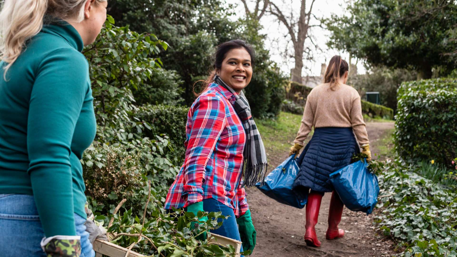 People smiling and carrying boxes with plants