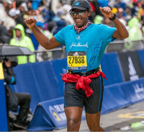 A member of the John Hancock Non-Profit Program crosses the finish line of the Boston Marathon 