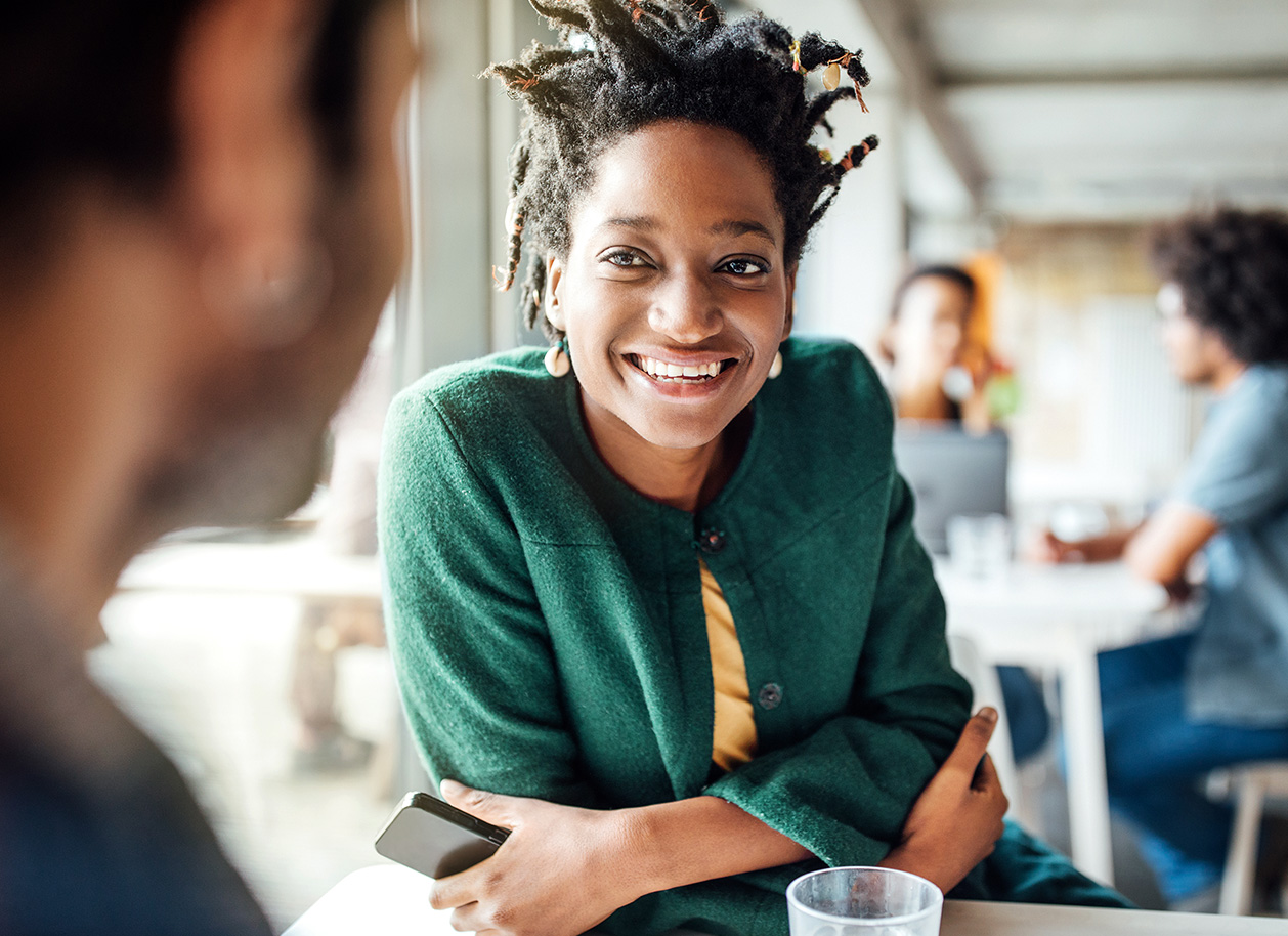 Woman in a green coat smiling in a restaurant