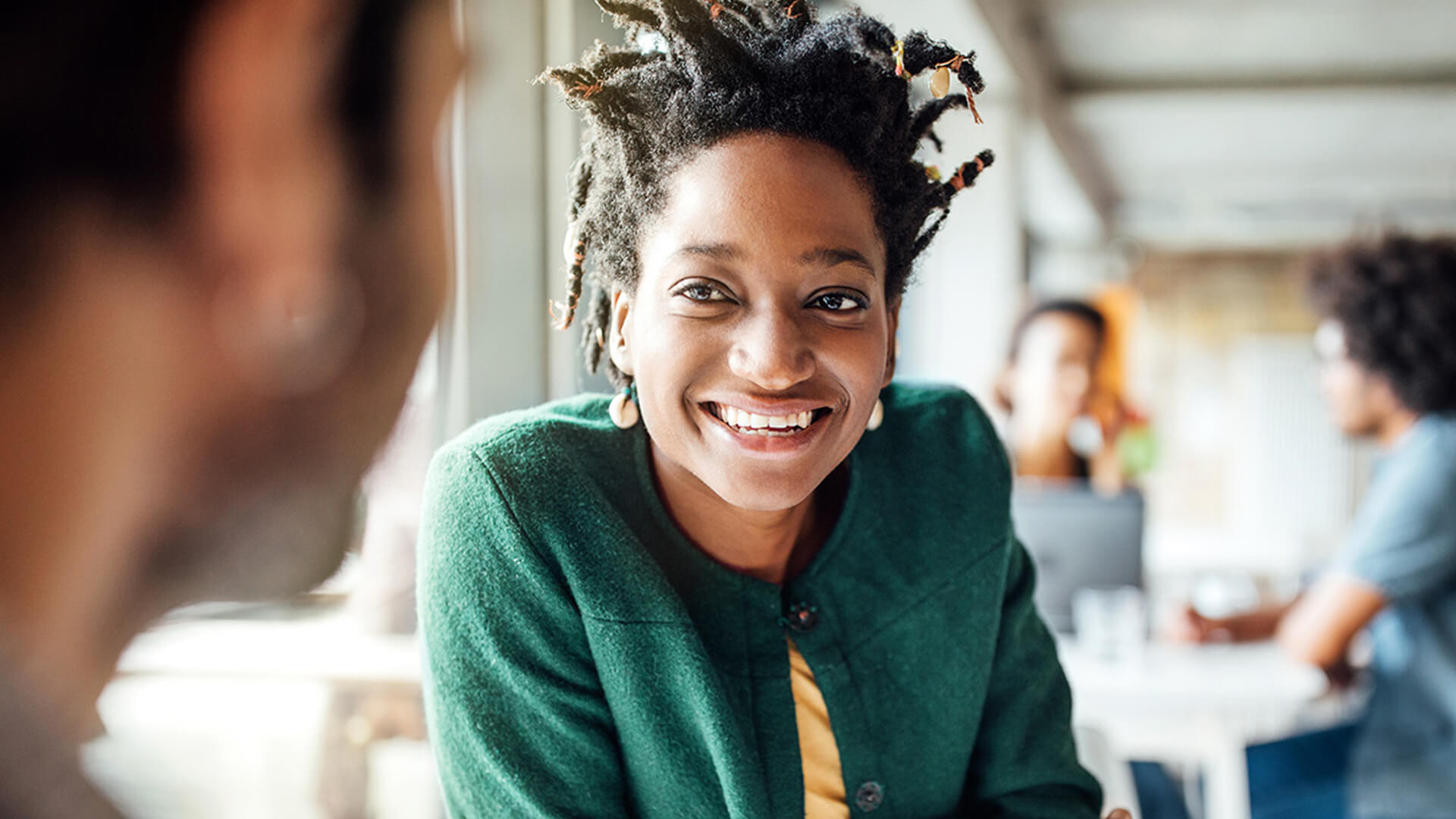Woman in a green coat smiling in a restaurant