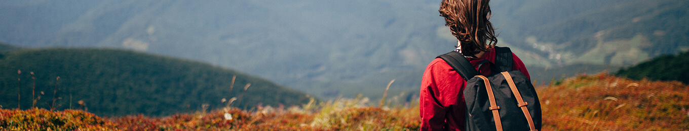Young woman in a red shirt on a hiking path in the mountains