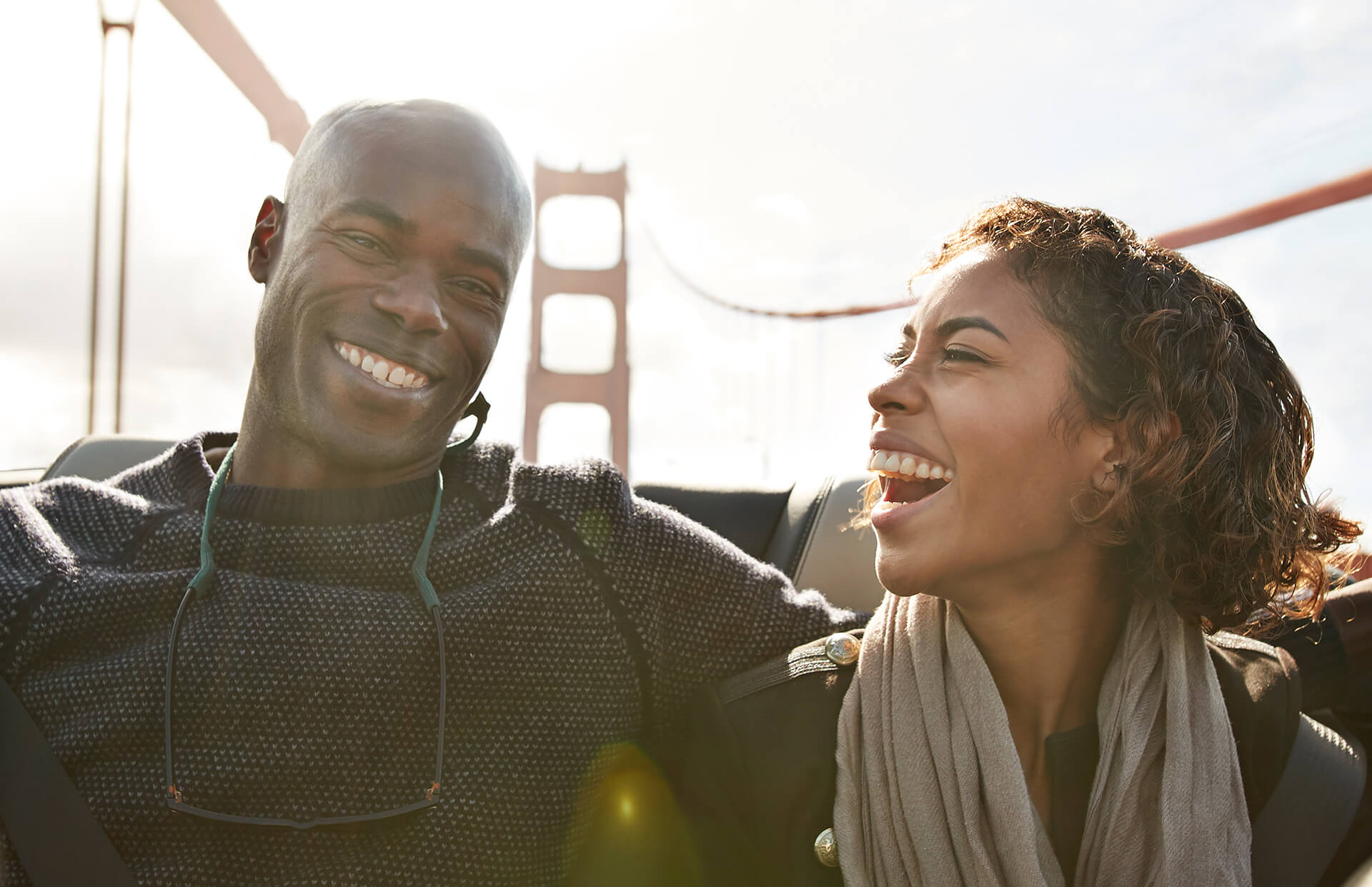 Couple laughing in the backseat of a convertible car on the Golden Gate Bridge, San Francisco, USA