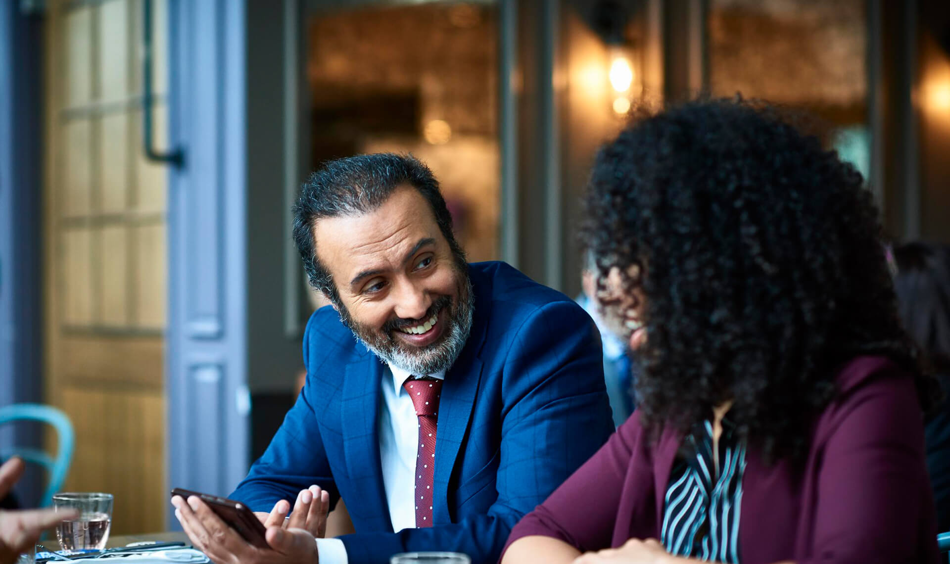 Businessman showing a businesswoman something on his cellphone at a table in a restaurant 