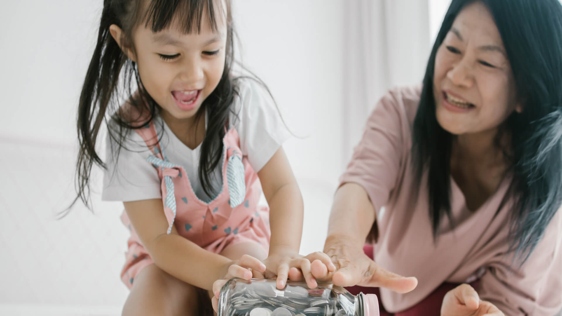 Grandmother and her granddaughter collecting coins in a glass jar