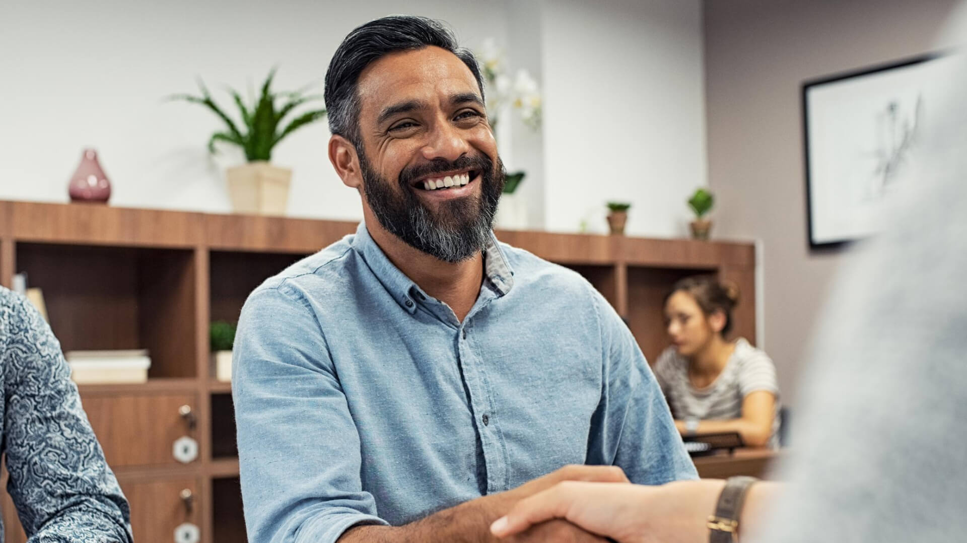 A man in an office setting shaking hands with a co-worker