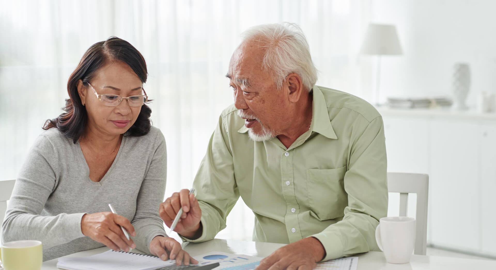 A woman and her father sitting down and discussing documents at a table together