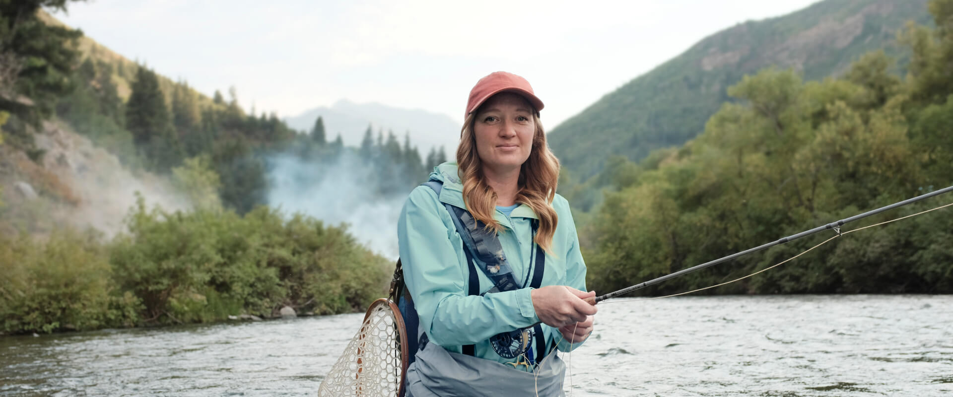 Woman in a hat and athletic clothes fly fishing in a river