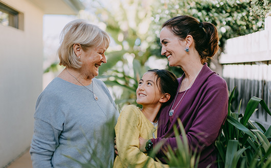Two women, one with a child, looking at each other and smiling.