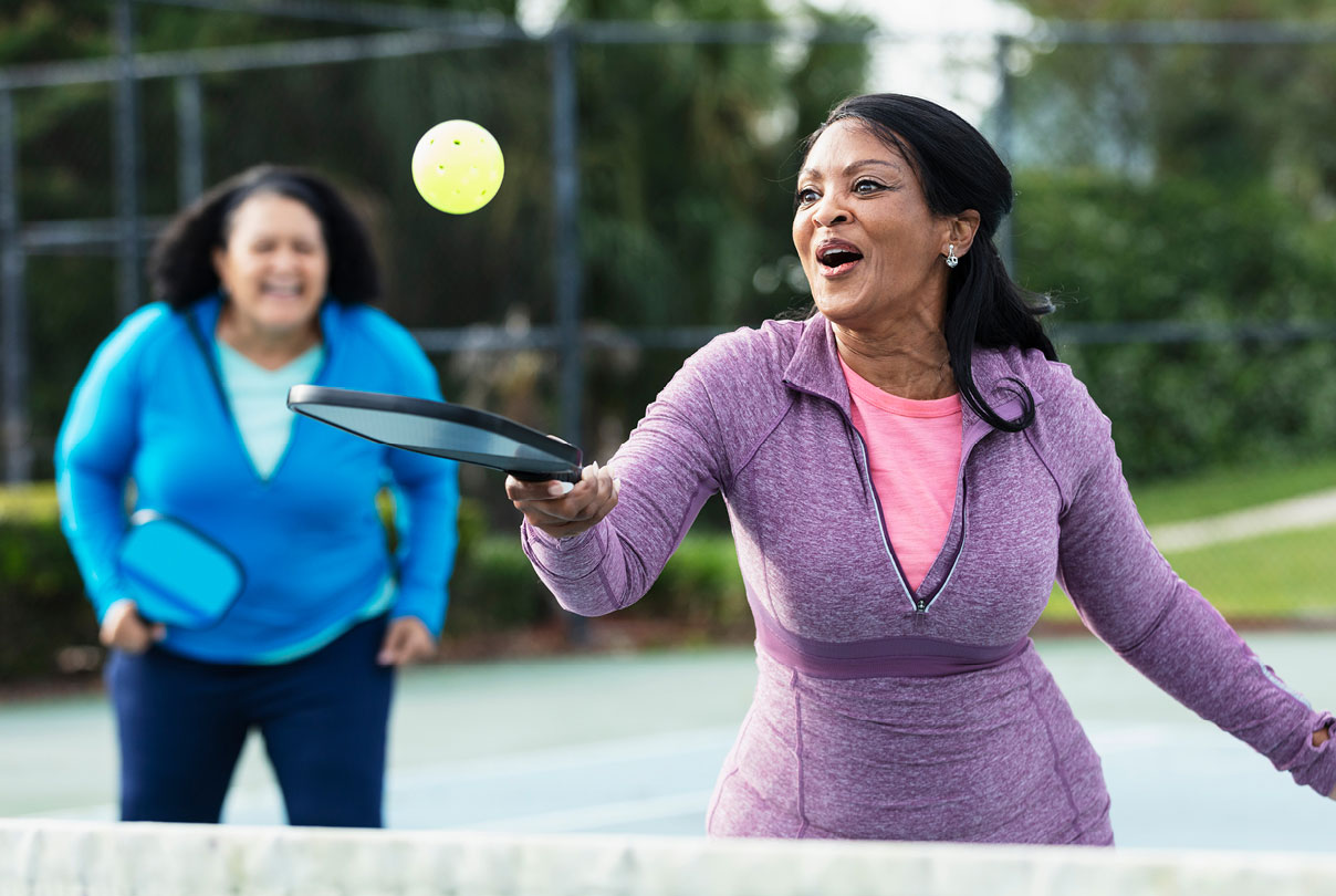Two people playing tennis, representing active lifestyle and healthy habits for longevity and well-being.