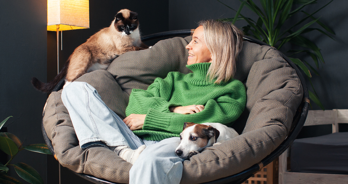 Woman relaxing with cat and dog in cozy home, illustrating strengths in longevity areas like care and social connection.