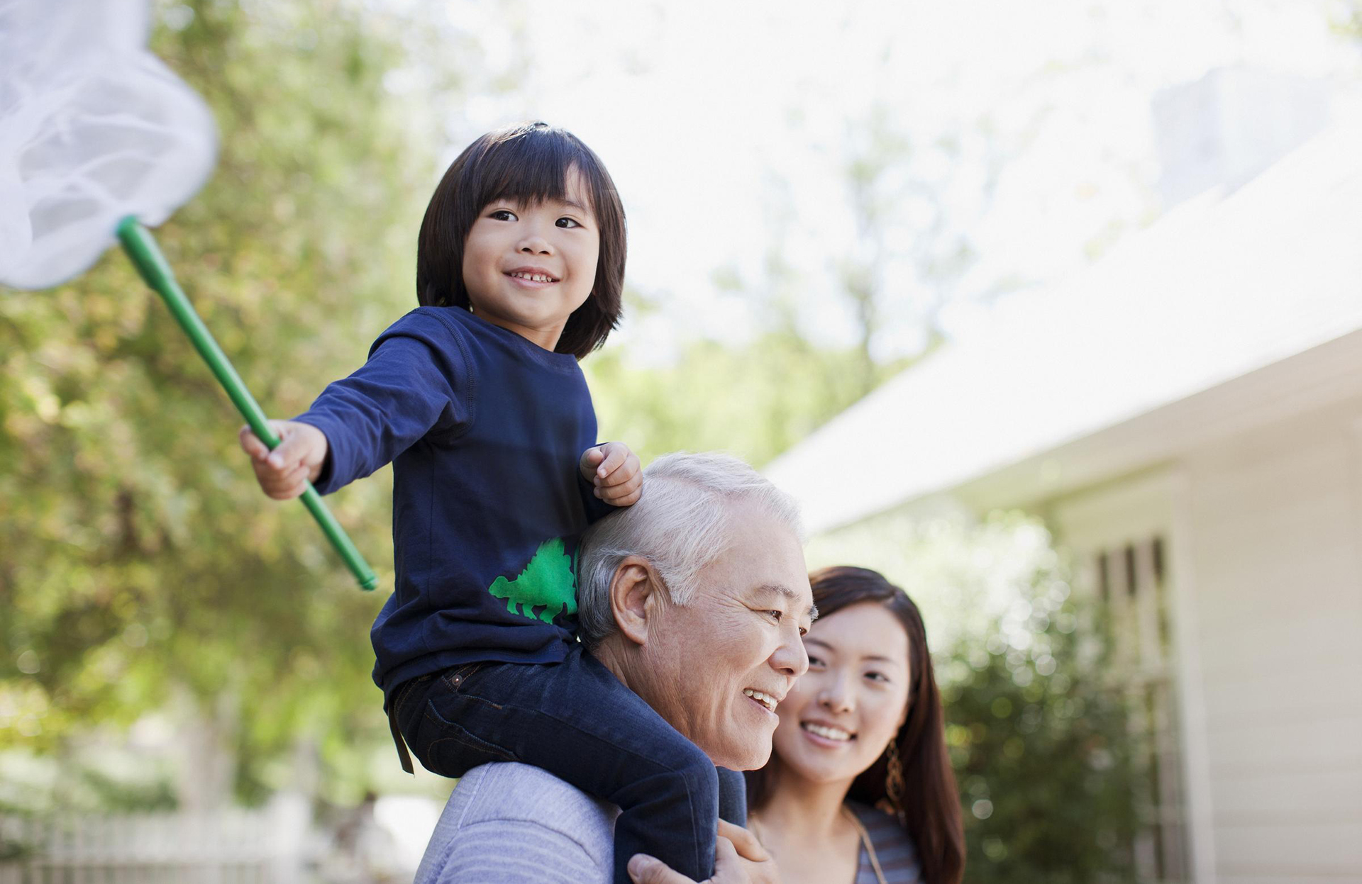 Grandchild with net on grandfathers shoulders with mother in background