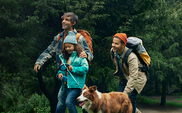 Family and dog smiling and walking in nature