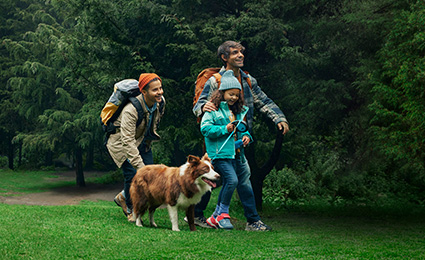 Family and dog smiling and walking in nature